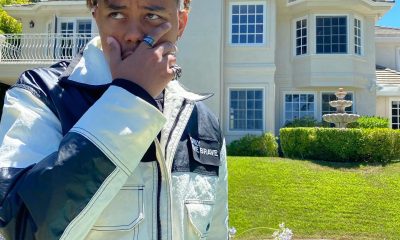 rapper cordae poses in front of mansion