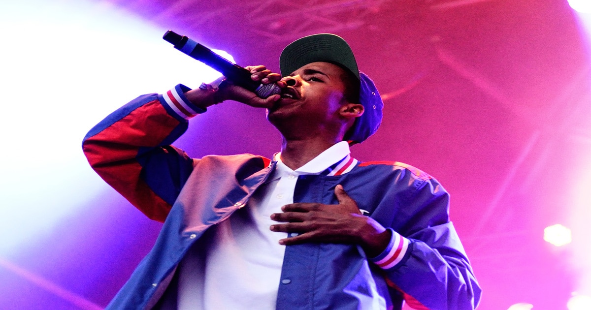 rapper earl sweatshirt signing into microphone while holding hand on heart