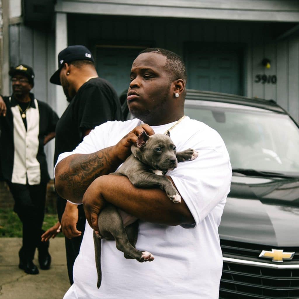Morray holding his dog in front of a car.