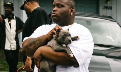 Morray holding his dog in front of a car.