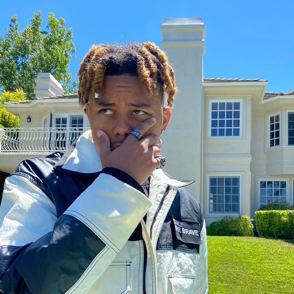 rapper cordae poses in front of mansion