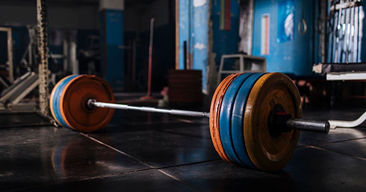 Close up of a barbell laying on the floor in an empty gym
