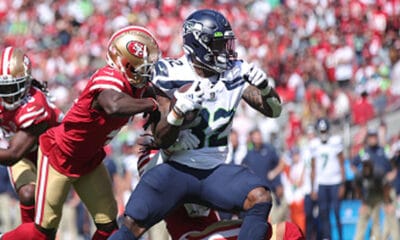 Fred Warner #54 and Emmanuel Moseley #4 of the San Francisco 49ers tackle Chris Carson #32 of the Seattle Seahawks