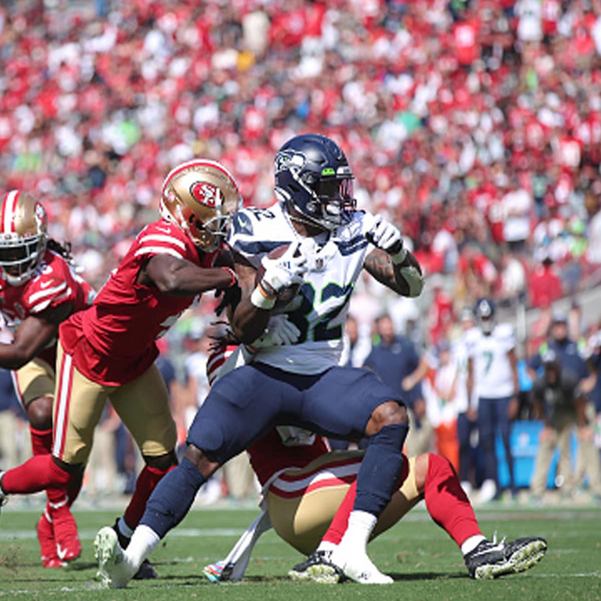 Fred Warner #54 and Emmanuel Moseley #4 of the San Francisco 49ers tackle Chris Carson #32 of the Seattle Seahawks