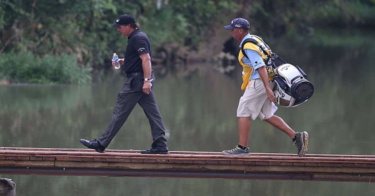 Phil Mickelson and his caddie cross the bridge to the ninth tee box during the fourth round of the PGA Championship 